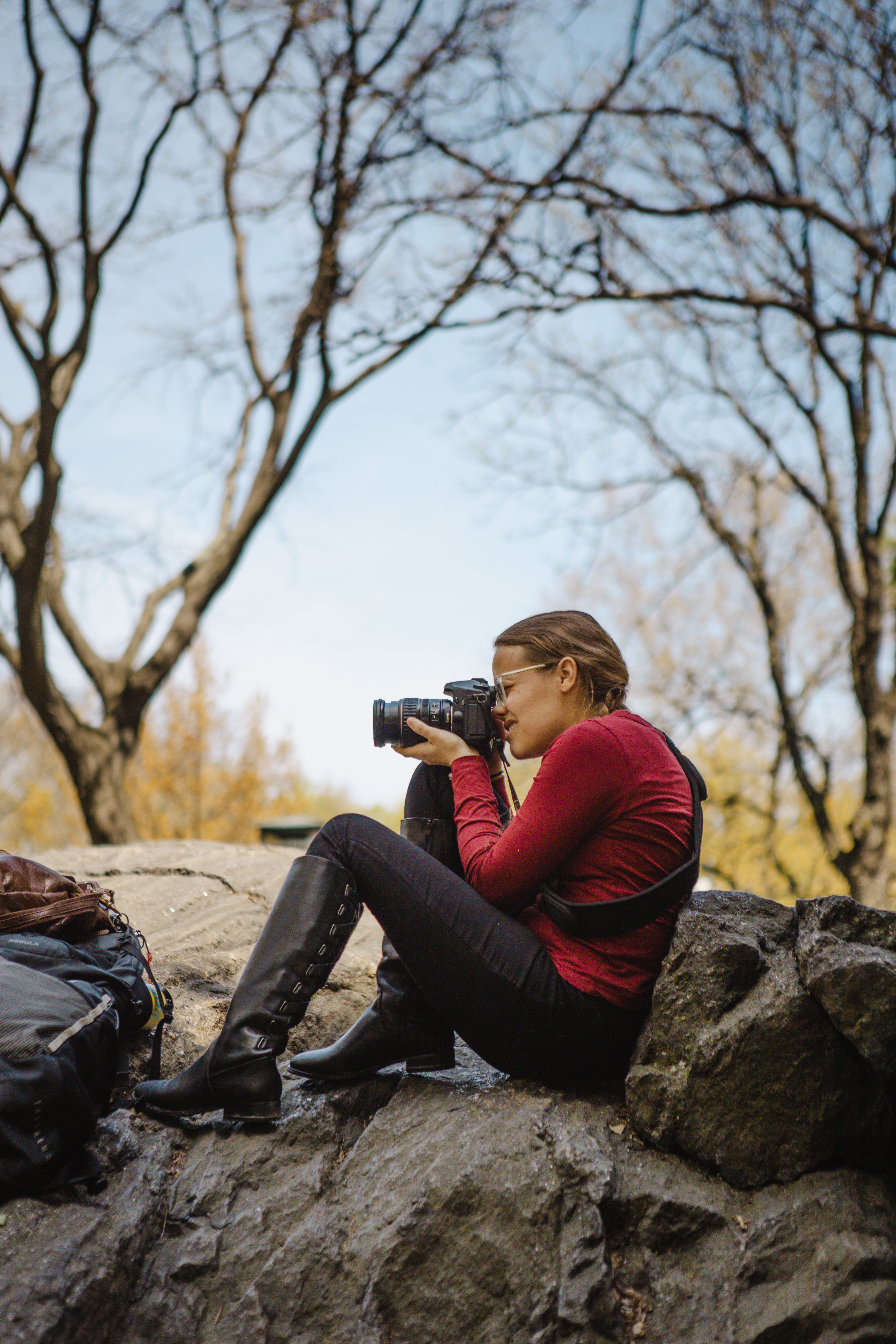 Girl sitting on rocks taking photographs.