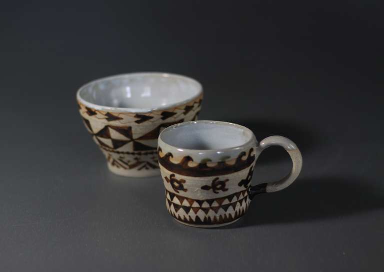 A bowl and a cup with polynesian designs.