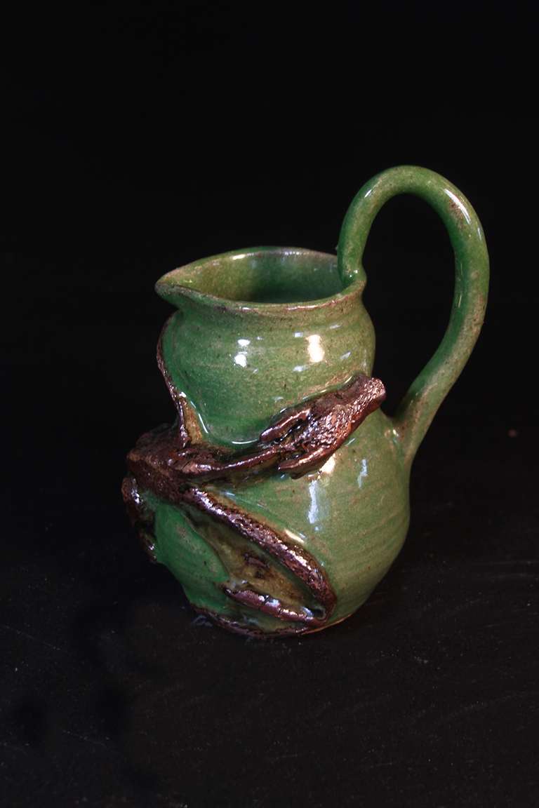 Ceramic pitcher with a sculpted wyvern on the surface.